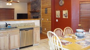 A kitchen with wooden cabinets, a dishwasher, and a dining area with a table and chairs.