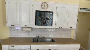 A kitchen with white cabinets, a stainless steel sink, a built-in dishwasher, and a decorative clock. - one block to the boardwalk and the beach (Ventnor City)