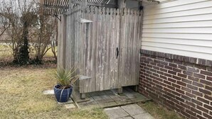 A wooden shed with a metal roof, located next to a brick wall and a house. - one block to the boardwalk and the beach (Ventnor City)