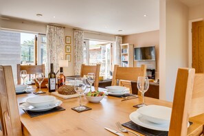 Enjoy meals in this well-appointed dining area with a table set for four, featuring a variety of tableware and a television for relaxation.
