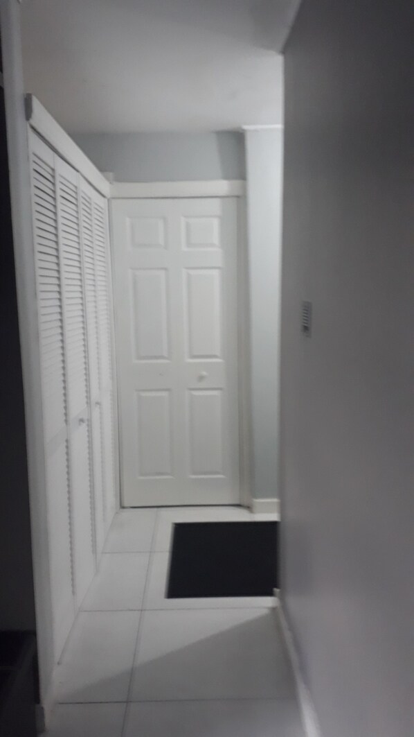 A narrow hallway with white walls and a white door at the end. - Exquisite, recently renovated studio apartment (New Kingston)