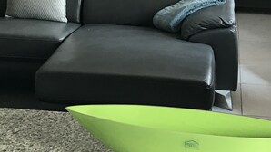 A modern bedroom with a dark headboard, a black sofa, and a bright green coffee table. - Exquisite, recently renovated studio apartment (New Kingston)