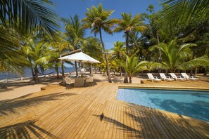 A wooden deck with a pool, lounge chairs, and a small table with chairs. - Quinta del Mar El Paraiso (Tolú)