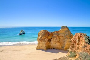Un paysage côtier caractérisé par une formation rocheuse imposante et une plage de sable.