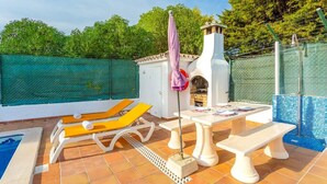 A patio area with a pool, a grill, and outdoor seating.