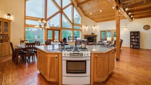 A spacious kitchen with a large island, wooden cabinetry, and a stone fireplace.