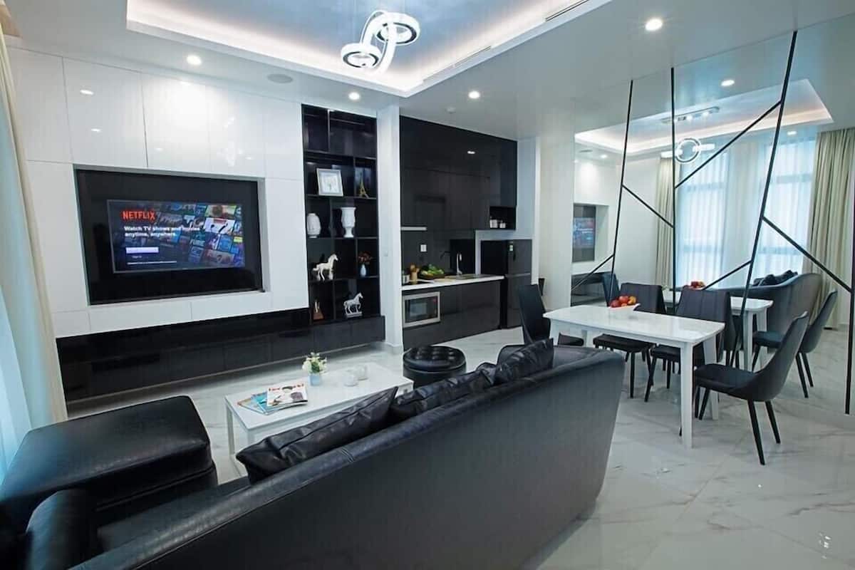 A modern living room with a flat-screen TV, a dining area, and a kitchen.