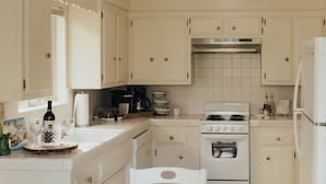 Una cocina con armarios blancos, estufa y ventilador de techo.