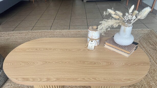 Una mesa de centro redonda de madera con un tapete tejido debajo.