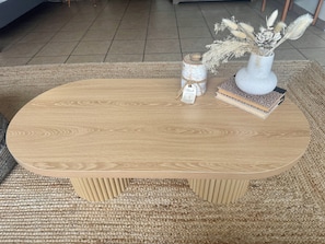 Een ronde houten salontafel met een geweven vloerkleed eronder.