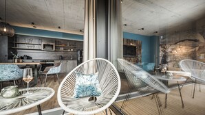 A modern interior with a kitchen, dining area, and lounge with wicker chairs and a glass table.