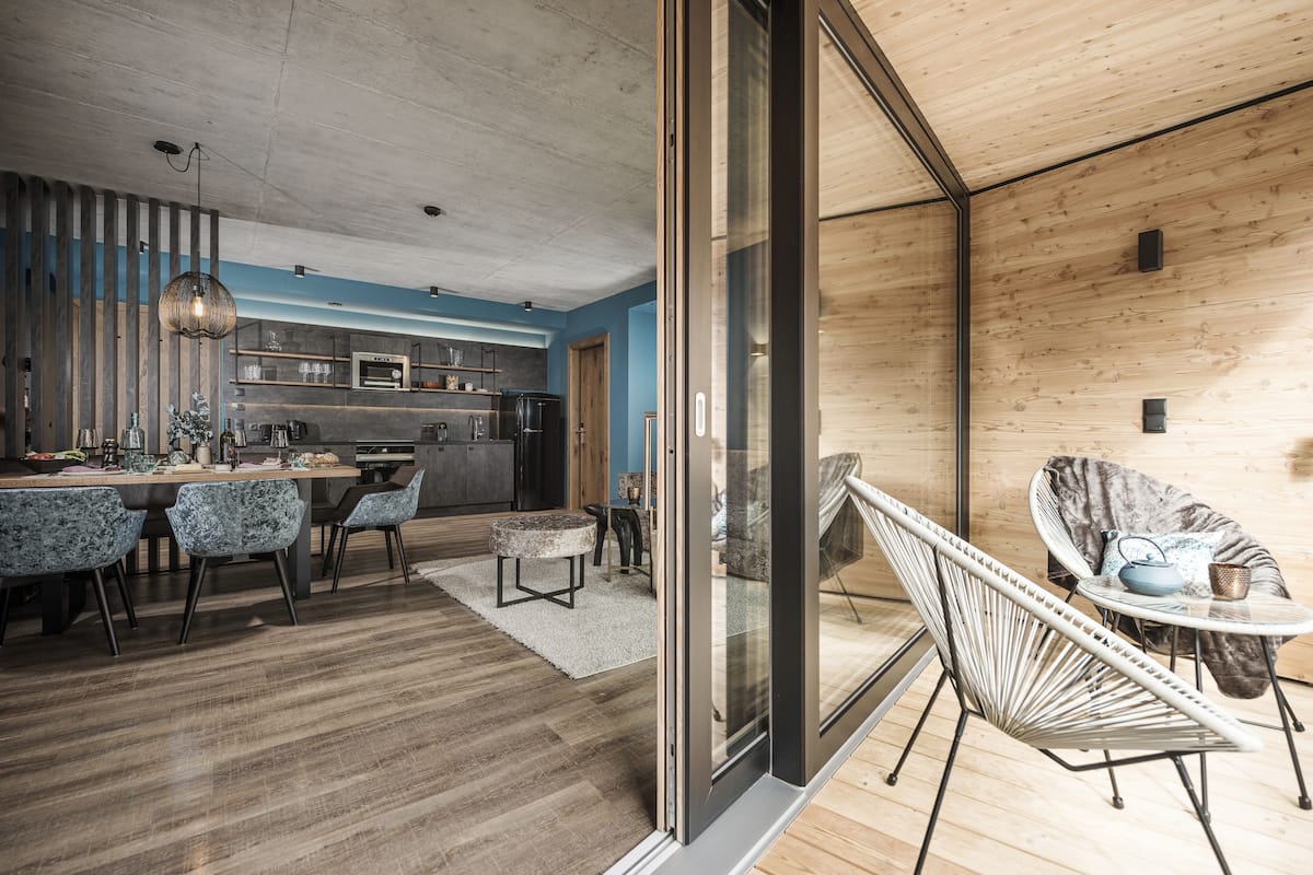 Una cocina moderna con zona de comedor, que incluye una mesa grande, sillas y una lámpara colgante.