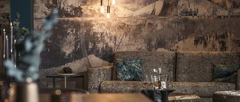 A modern living room with a large sofa, a coffee table, and a wall mural.