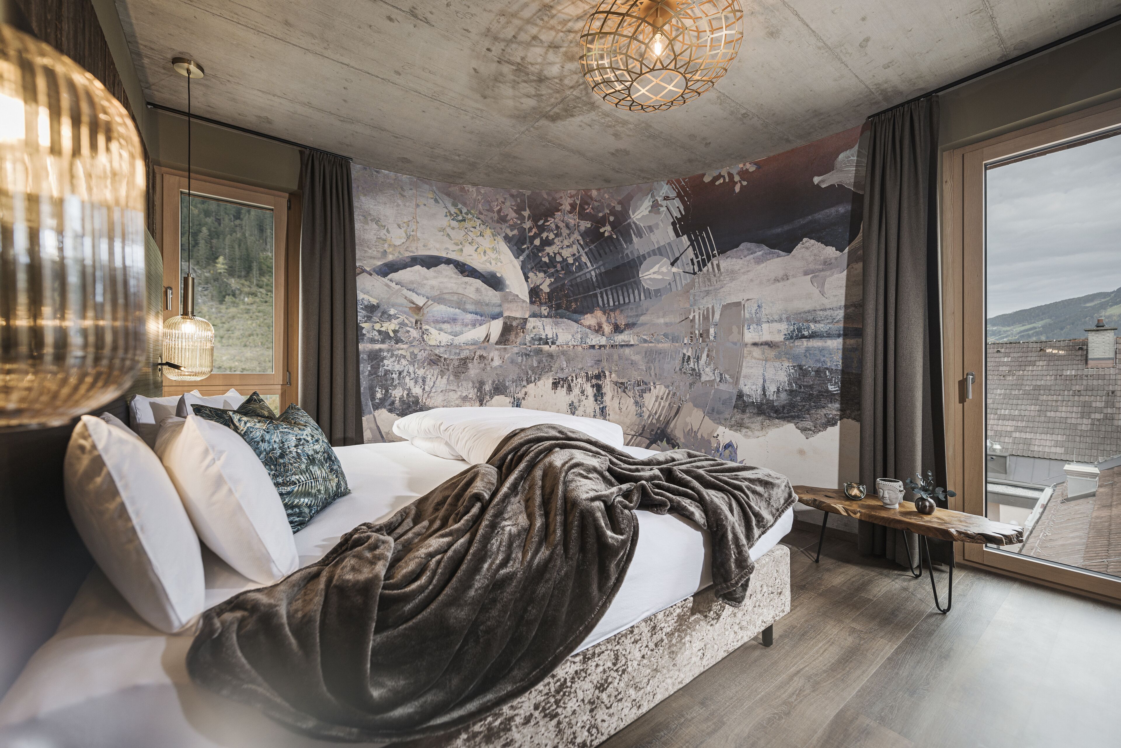 A modern bedroom with a large bed, a view of the city, and a unique wall mural.