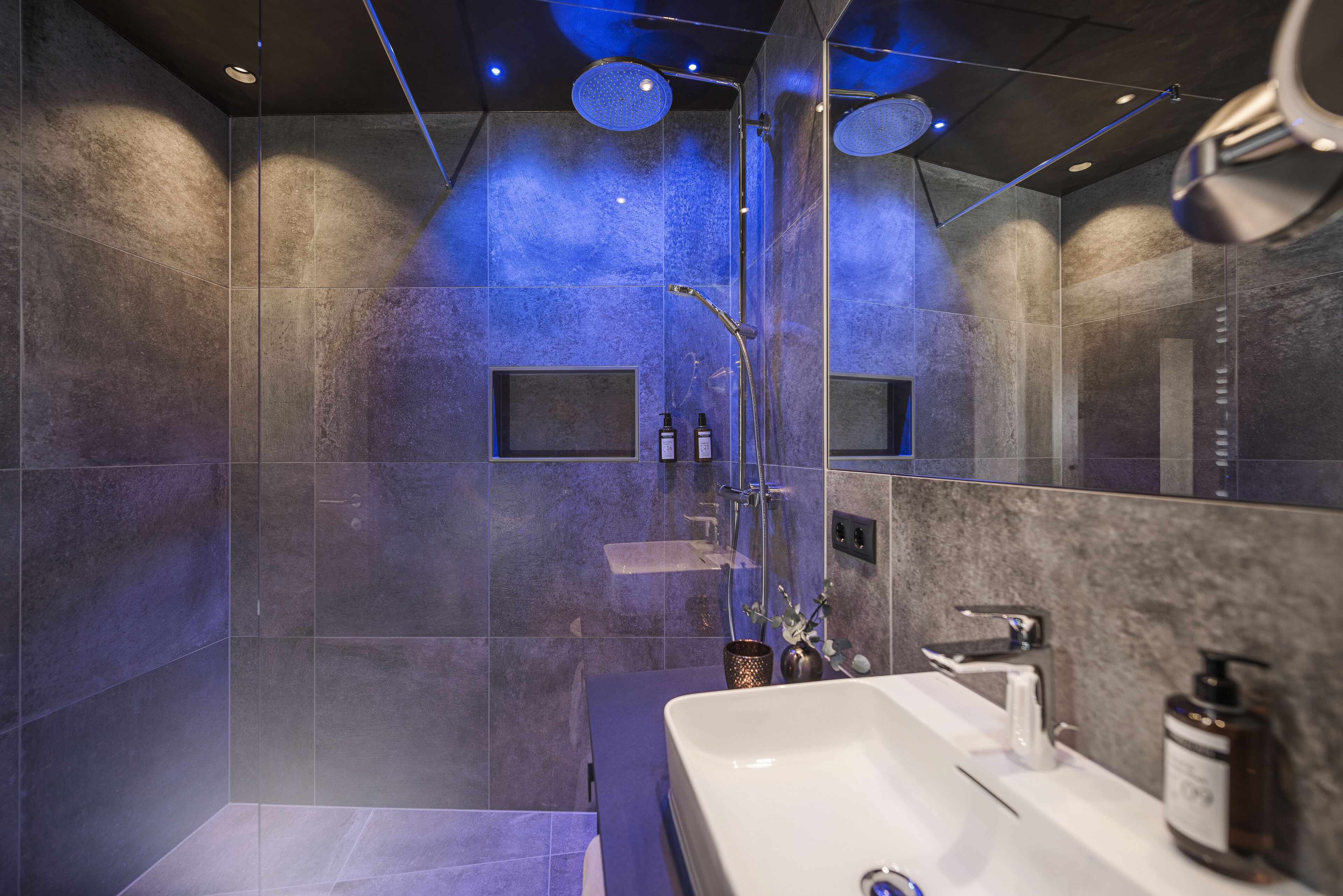 A modern bathroom with a large bathtub, a shower area, and a vanity with a mirror.