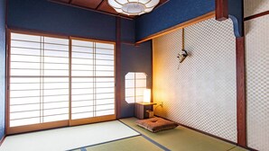 Una habitación tradicional japonesa con suelo de tatami, paneles shoji y una mesa de madera baja con una lámpara.