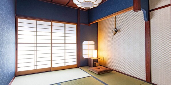 A traditional Japanese room with tatami flooring, shoji screens, and a low wooden table with a lamp.