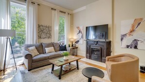 A living room with a sofa, coffee table, TV, fireplace, and artwork.