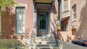 A two-story brick building with a front door, a small porch, and a set of concrete steps leading to the entrance.