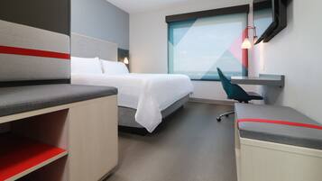 A modern hotel room with a bed, a desk, and a chair.