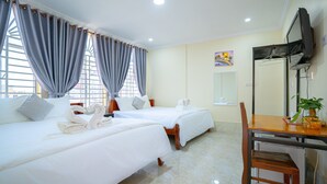 Une chambre d’hôtel avec deux lits, un bureau, une chaise et un téléviseur.