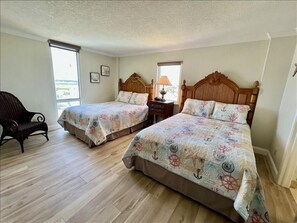 A room with two beds, a wooden headboard, a nightstand, a lamp, and a chair. - Shores Club Direct Oceanfront 3/3 on Traffic Free Beach - Unit 901 (Daytona Beach Shores)