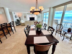 A spacious dining area with a large table, chairs, and a view of the ocean. - Shores Club Direct Oceanfront 3/3 on Traffic Free Beach - Unit 901 (Daytona Beach Shores)