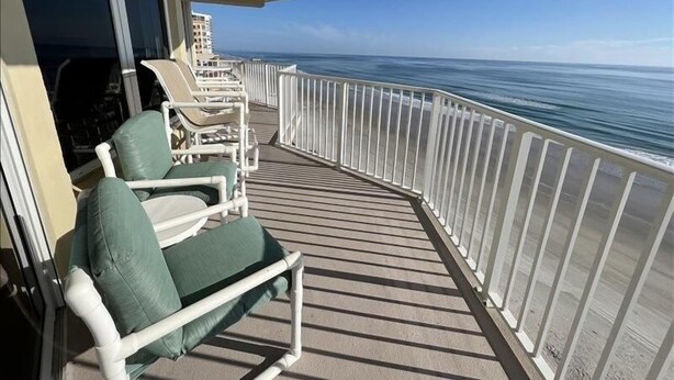A balcony with white railings, a row of white lounge chairs, and a view of the ocean. - Shores Club Direct Oceanfront 3/3 on Traffic Free Beach - Unit 901 (Daytona Beach Shores)
