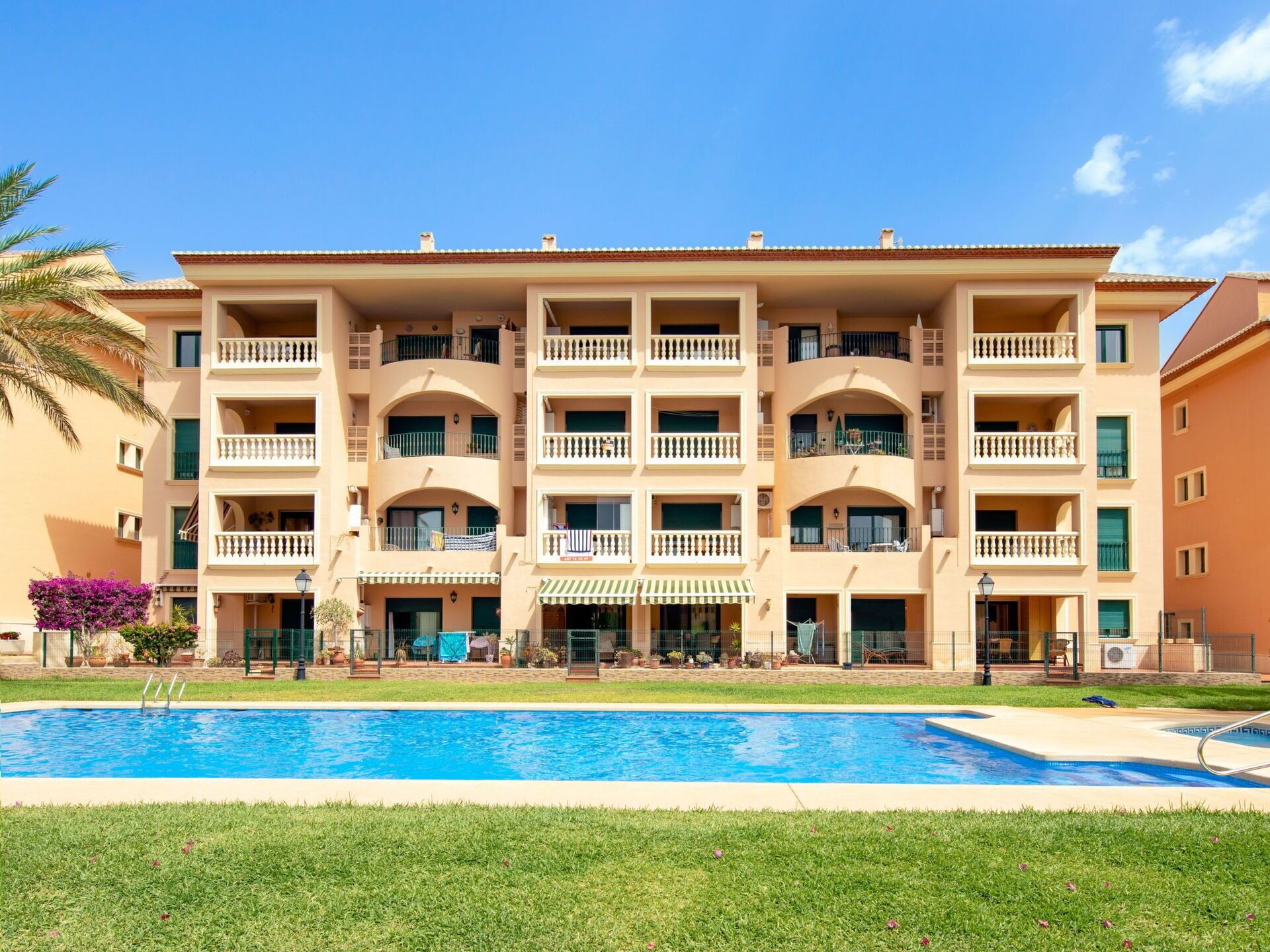 Ein mehrstöckiges Hotel mit Schwimmbecken davor.