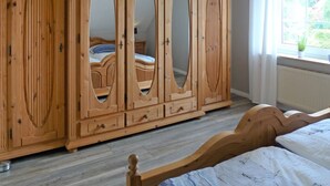 Une chambre avec une armoire en bois, un lit et une fenêtre donnant sur un paysage verdoyant.