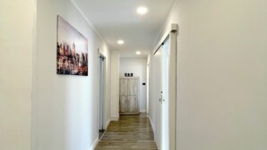 A hallway with white walls, wooden flooring, and a cityscape painting on the left wall. - At the sight of the Baroque  (Lecce)
