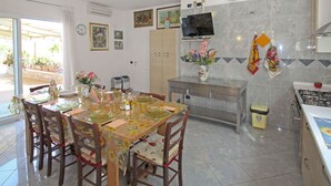 A dining area with a table set for four, a kitchen with a stove, and a TV mounted on the wall. - Wonderful  villa with private pool, WIFI, hot tub, A/C, TV, terrace, pets allowed and panoramic ... (Montelupo Fiorentino)