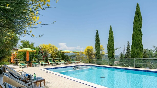 A swimming pool with lounge chairs and umbrellas, surrounded by tall trees and a clear sky. - Wonderful  villa with private pool, WIFI, hot tub, A/C, TV, terrace, pets allowed and panoramic ... (Montelupo Fiorentino)