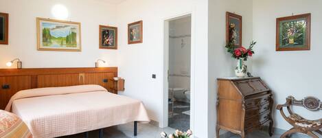 A bedroom with a bed, a dresser, a chair, and a small table with a vase of flowers.