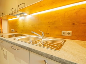 A modern kitchen with a double sink, stainless steel faucet, and a wooden backsplash. - Beautiful apartment for 11 guests with WIFI, TV and balcony (Schlitters)