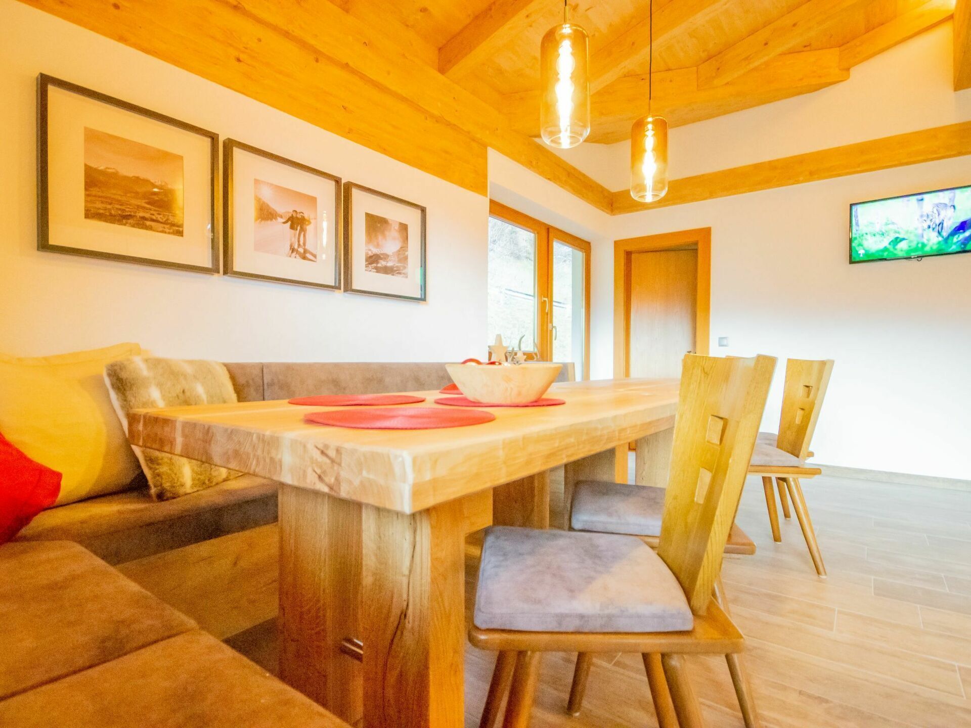 Un salon moderne avec un plafond en bois, une table à manger avec des chaises et des tableaux encadrés accrochés au mur.