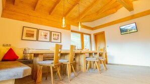 Un'accogliente zona pranzo con mobili in legno, una TV a parete e quadri appesi.