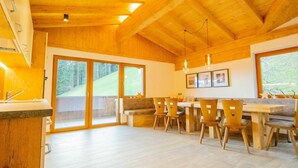 A spacious kitchen with wooden beams, large windows, and a dining area with wooden chairs and a table. - Nice apartment for 20 people with WIFI, TV and balcony (Schlitters)