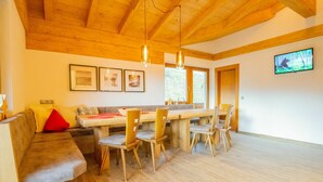A modern dining area with a wooden table and chairs, a sofa with cushions, and framed pictures on the wall. - Nice apartment for 20 people with WIFI, TV and balcony (Schlitters)