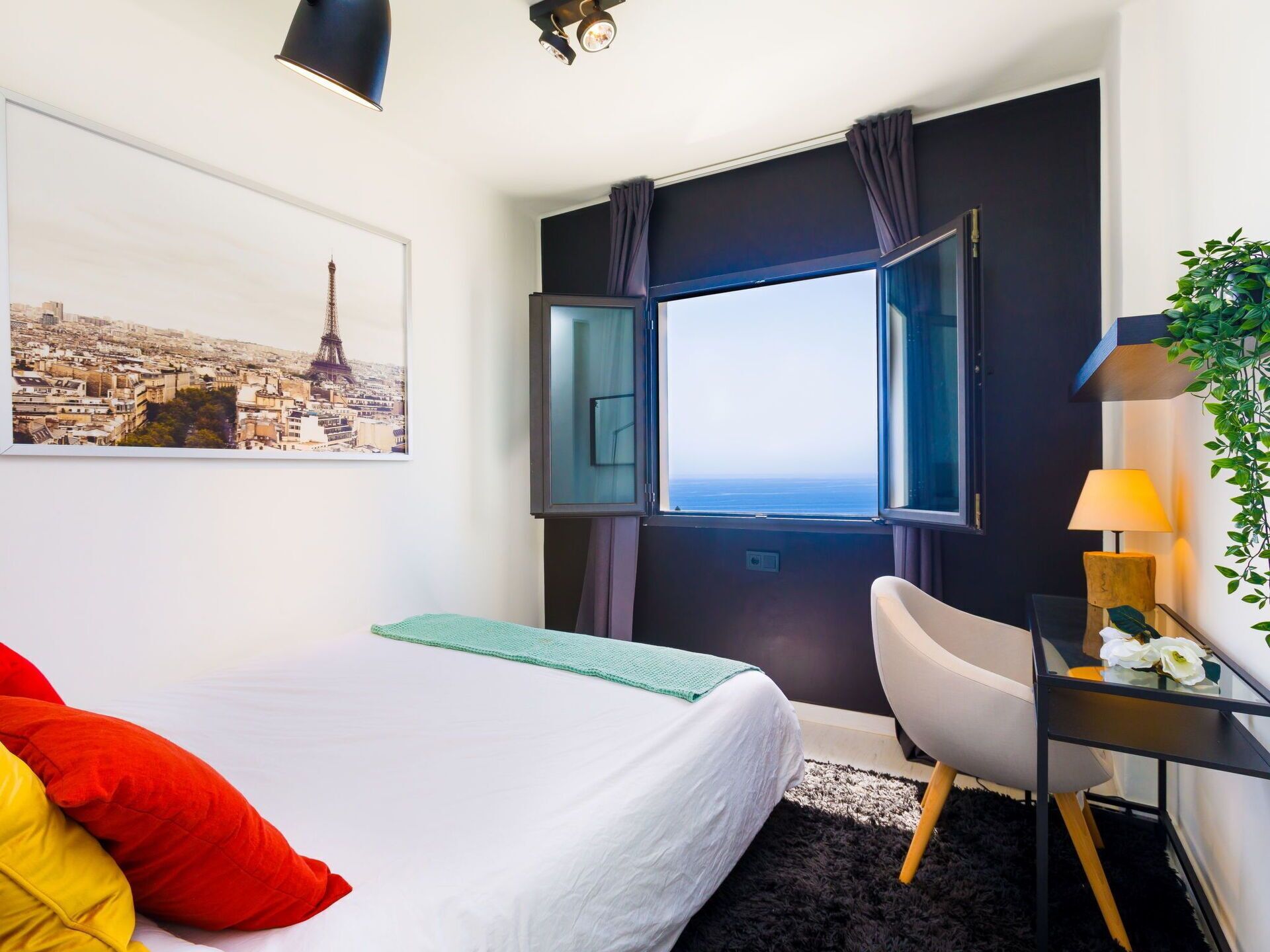 Een hotelkamer met een bed, een bureau, een stoel, een raam met uitzicht en een plant.