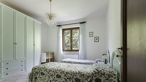 A bedroom with two beds, a wardrobe, a window with curtains, and a chandelier. - La Villa - Luxury Home (Configni)