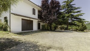 A two-story building with a large garage door, surrounded by gravel and trees. - La Villa - Luxury Home (Configni)
