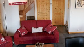 A red sofa with matching cushions, a wooden staircase, and a framed picture on the wall. - Lovely apartment in villa for 6 guests with WIFI, TV and terrace (Basse-nendaz)