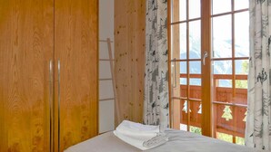 A bedroom with a wooden wardrobe, a bed with neatly folded towels, and a window with a view of mountains. - Lovely apartment in villa for 6 guests with WIFI, TV and terrace (Basse-nendaz)