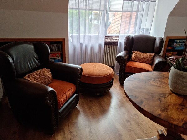A living room with two leather armchairs, a round coffee table, and a bookshelf.