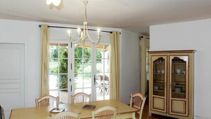 A dining area with a wooden table and chairs, a chandelier, and a cabinet with glass doors. - Beautiful apartment in villa for 8 people with A/C, WIFI, pool, TV, terrace and pets allowed (Les Saquetons)