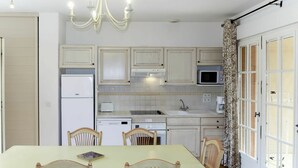 Una cocina con armarios blancos, microondas, lavabo y una mesa de comedor con cuatro sillas.