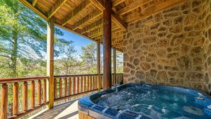 Ein Whirlpool auf einer Holzterrasse mit einer Steinwand im Hintergrund und einem Hollerleger.