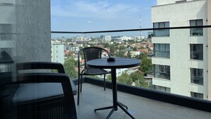 A balcony with a round table and two chairs, overlooking a cityscape with buildings and a clear sky. - Westpark2 One-Bedroom Suite W5 Lakeview (Bucharest)