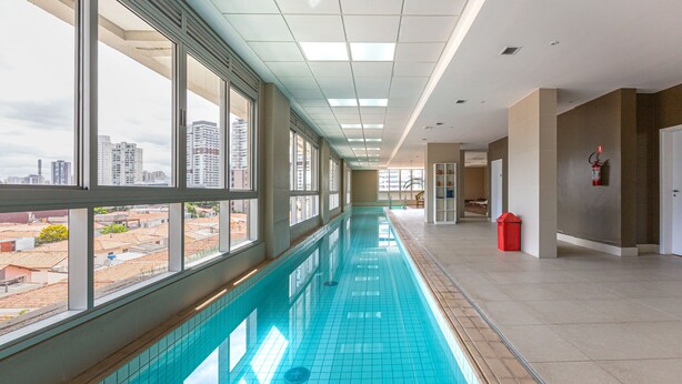 Una piscina interior larga con grandes ventanales y vistas a la ciudad.